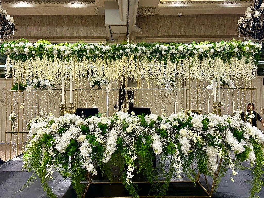 Mesa principal de boda bajo una cascada de flores blancas